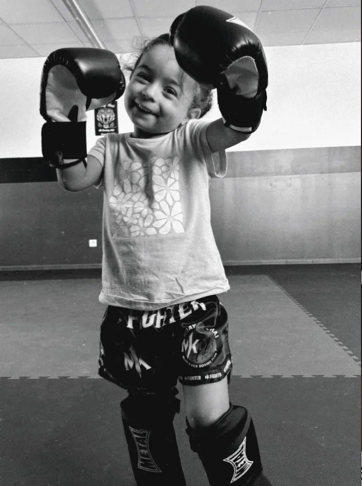 Enfant souriante portant des gants de boxe dans la salle du MK Boxing Club